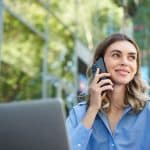portrait young businesswoman sitting outside park talking mobile phone using laptop young w
